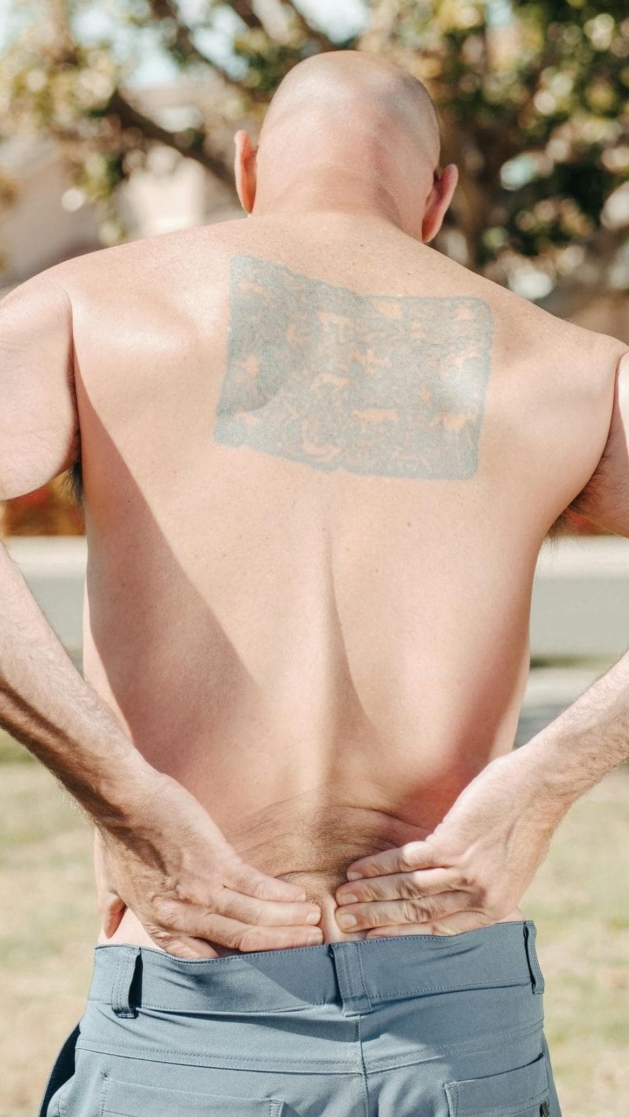 Hombre tocandose la espalda baja con dolor por un sindrome del piramidal