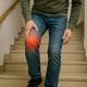 Persona bajando escaleras con gesto de dolor en la rodilla, síntoma común de artrosis o lesión articular.